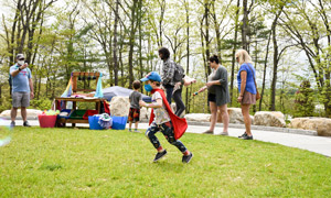 A child runs across the lawn of The Ramble with a cape on.