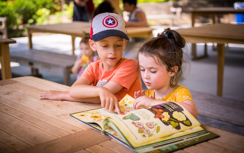 Children read a book in the Ramble.