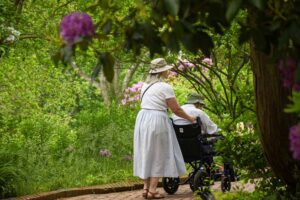 A visitor pushing someone in a wheelchair around the Lawn Garden.