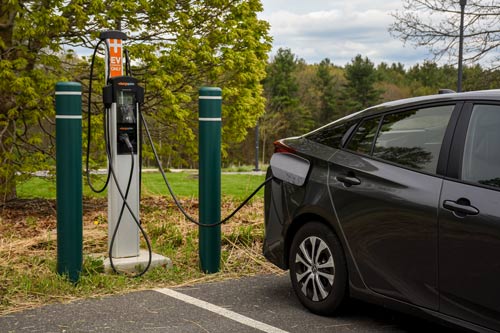A car is plugged into the electric charging station in the parking lot.