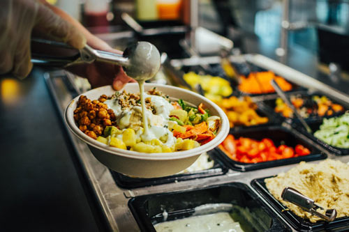 Fresh ingredients for a salad are put into a bowl for café visitors.