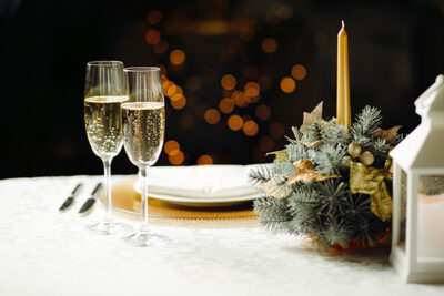 prosecco drinks on a table setting consisting of gold candles and holiday pines